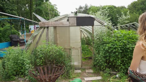 young blonde sustainable lady walks into organic farming greenhouse inside eco village living sustainably with nature