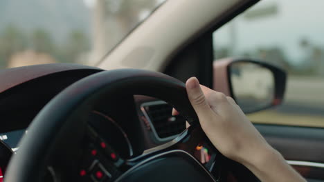 woman driving car with hands on steering wheel to control vehicle in city travelling on the road at rush hour to destination