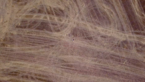 aerial view of a lone person in a vast, patterned dry field