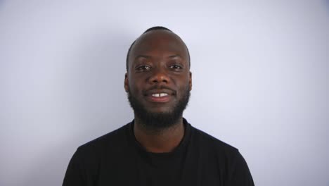 black male slowly looking up and smiling to camera with white background