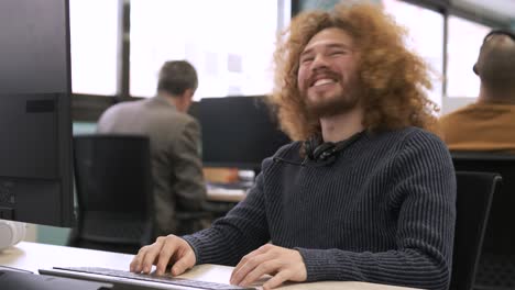 happy businessman using computer and talking as he enjoys work in creative office