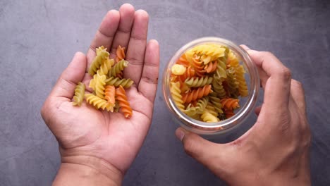 hands holding a glass jar with colorful pasta