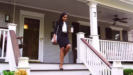 businesswoman with cup of coffee leaving suburban house for work