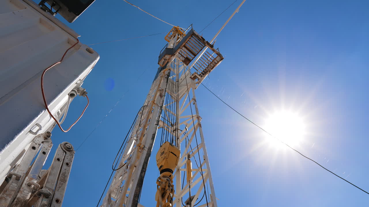 Looking at the derrick with working rotating boer. Low angle view at the tower near the wagon.