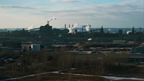 Industrial-complex-with-smokestacks-against-a-clear-sky,-winter-landscape