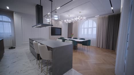 elegant open-plan living space combining a modern kitchen with marble flooring and a dining area with a unique chandelier