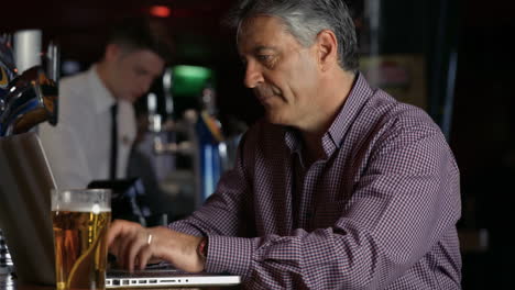 Frustrated-man-having-a-pint-at--the-bar-using-laptop-