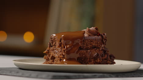 close up of melted chocolate sauce on slice of chocolate cake on plate being eaten