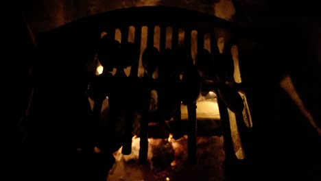 a top down view of wild foraged mussels slowly cook on an old grate ontop of an open log campfire in an old fireplace