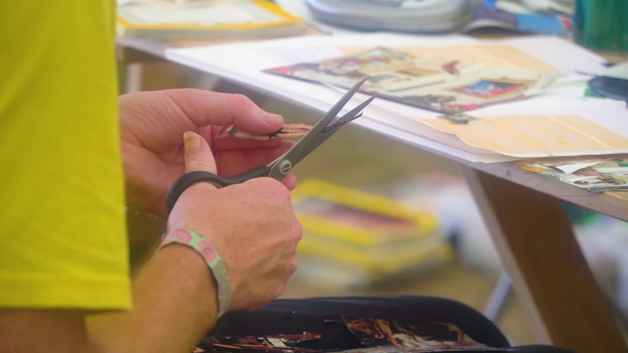 teenager in creative arts class is cutting various different types of newspapers and magazines putting together unique pieces of images and text close up hands summer music festival
