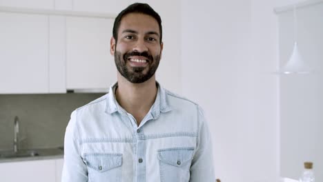 happy handsome dark haired latin man posing in kitchen