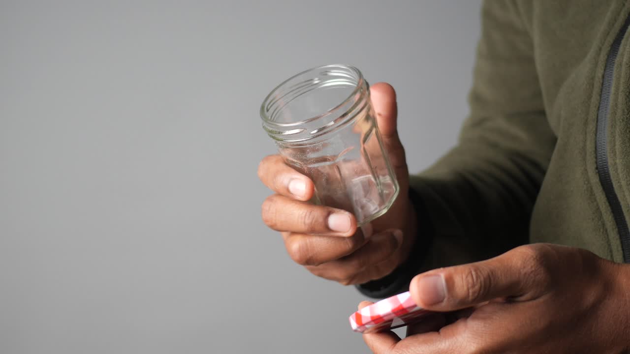 persona sosteniendo un frasco de vidrio con una tapa