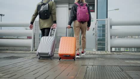 dos personas con equipaje caminando hacia el ascensor en el aeropuerto