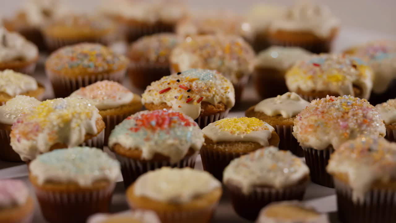 A close-up of numerous colorful cupcakes with frosting and sprinkles