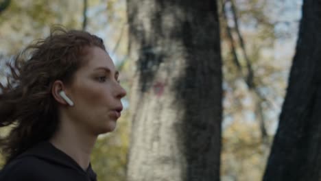 Mujer-Caucásica-Corriendo-En-El-Parque-En-Otoño-Con-Auriculares-En-Los-Oídos