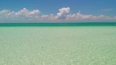 el dron vuela suavemente a través de una cabaña de playa de madera, luego se desliza sobre aguas azules prístinas