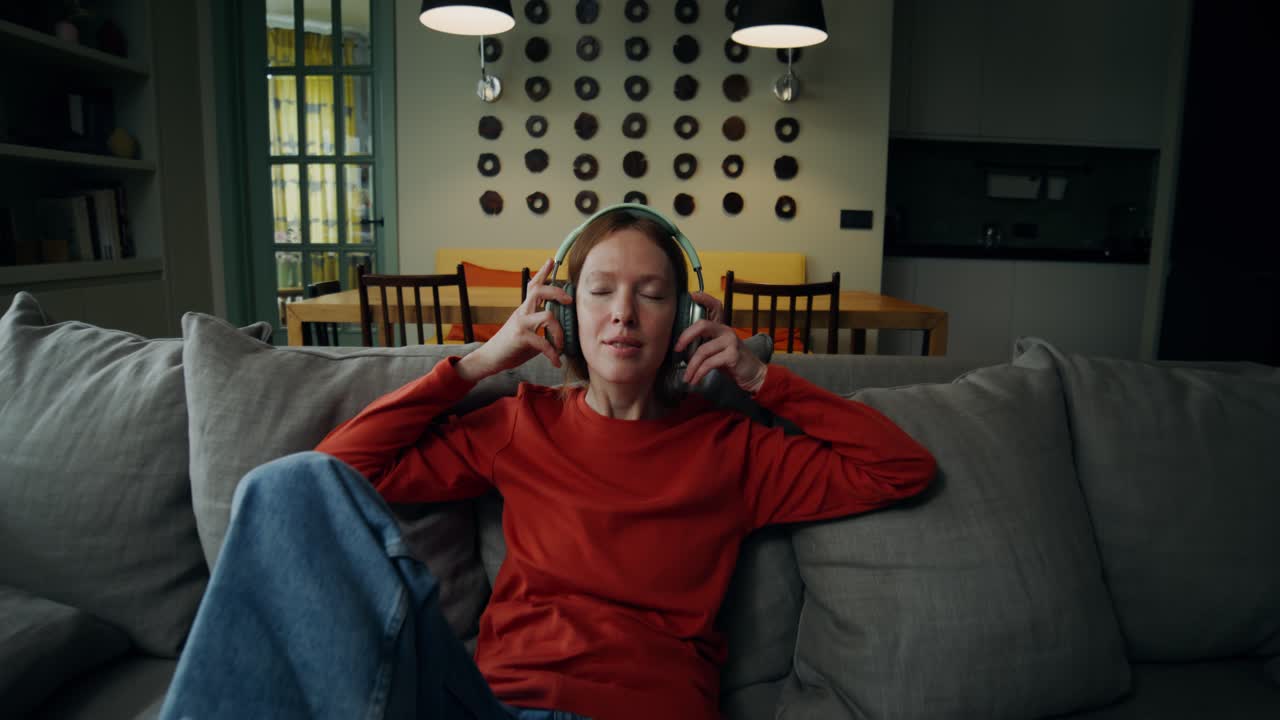 집 의 소파 에서 음악 을 듣고 있는 여자