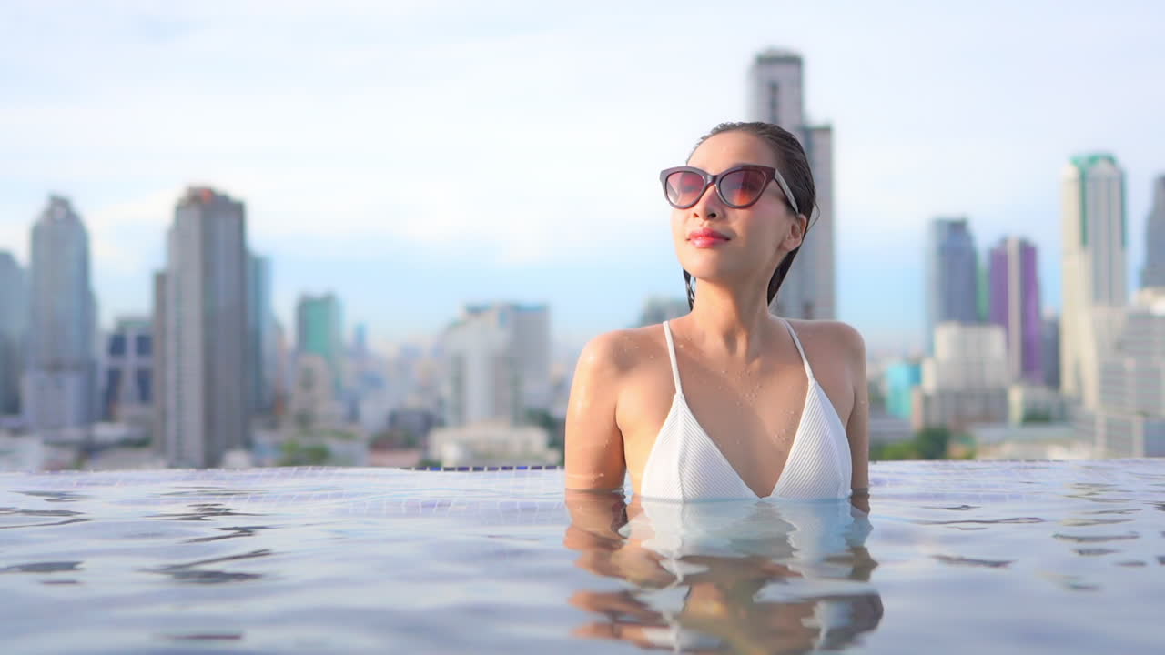일몰, 슬로우 모션 복사 공간에서 방콕 도시 스카이라인의 전망을 감상할 수 있는 옥상 수영장 안에 있는 여성
