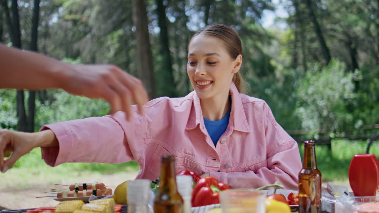 Woman help cooking barbeque vegetables to man in forest closeup. Smiling lady