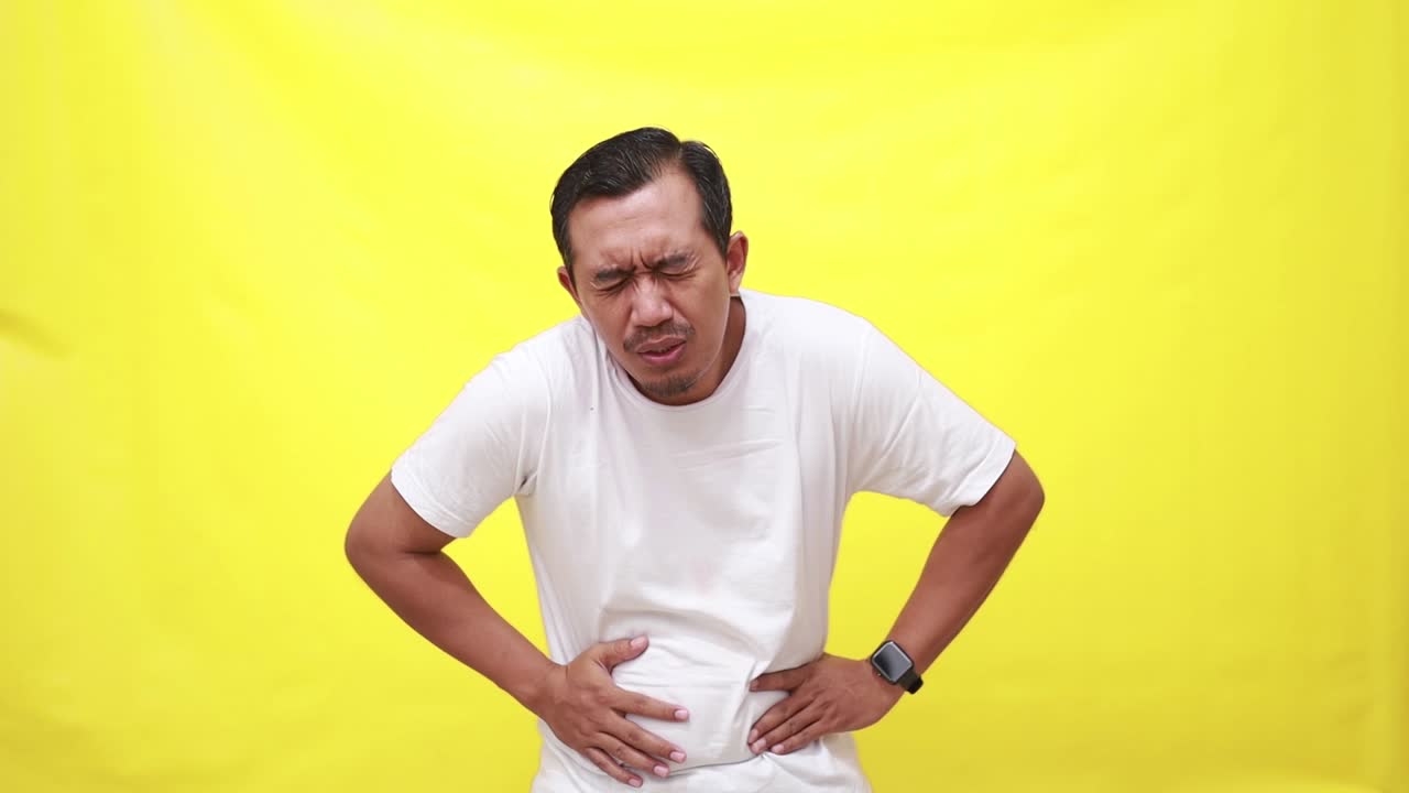 Man with abdominal pain health problem discomfort diarrhea isolated on yellow background