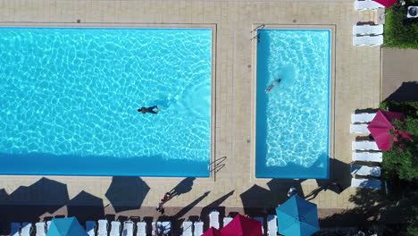 Large-outdoor-swimming-pool-with-people-in-vacation-drone-view-vertical