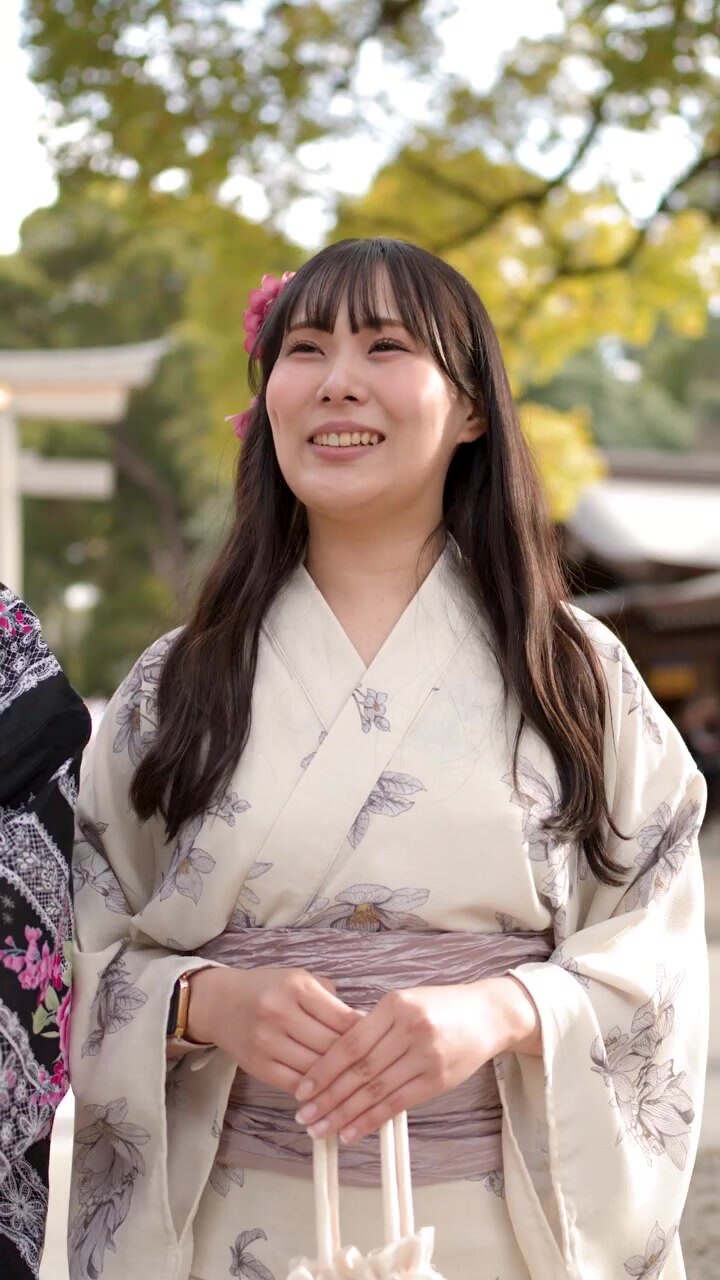 Due donne giapponesi in yukata tradizionali ridono e parlano all'aperto presso un santuario shintoista.