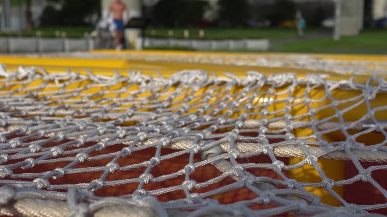 сеть для скалолазания в парке. игровое оборудование для детей. на заднем плане - люди, занимающиеся в парке