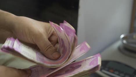 closeup shot of hands counting 2000 indian rupee banknotes, cash in hand, lots of cash