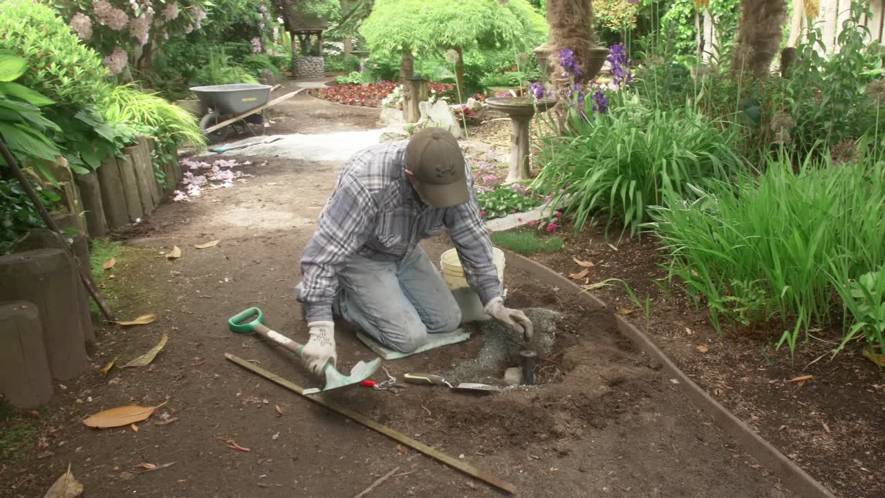 Gartner installerer et sprinkleranlegg langs en sti i en botanisk hage