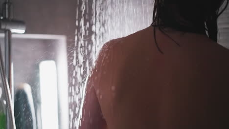 woman rests under shower sprays in bathroom closeup. lady takes washes body standing under liquid flow in washroom. comfort and relaxation at spa