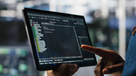 close up of data center software developer checking code on tablet