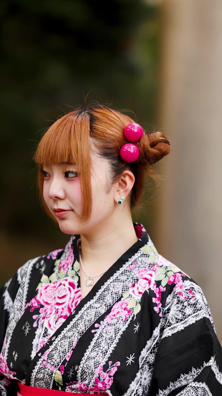 Una giovane donna che indossa un kimono floreale posa all'aperto a Harajuku, Tokyo, Giappone