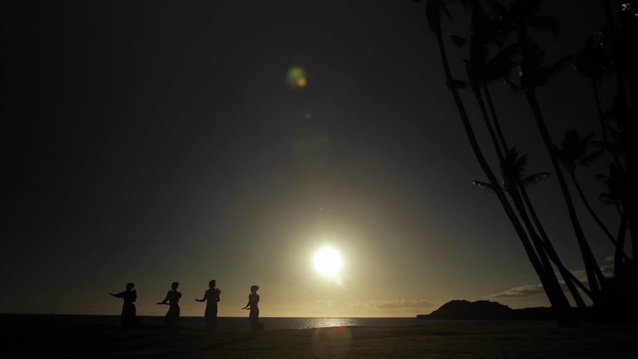 하와이 원주민 댄서들이 해질녘 멀리서 공연합니다.