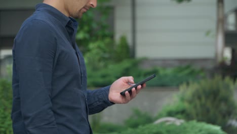 4k young man walks down street in city and uses smartphone