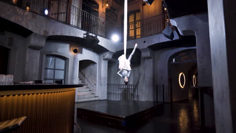 female aerialist doing the layover drop stunt on silks in a music club