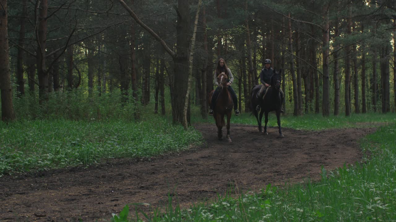 dos chicas jóvenes montando caballos en el bosque