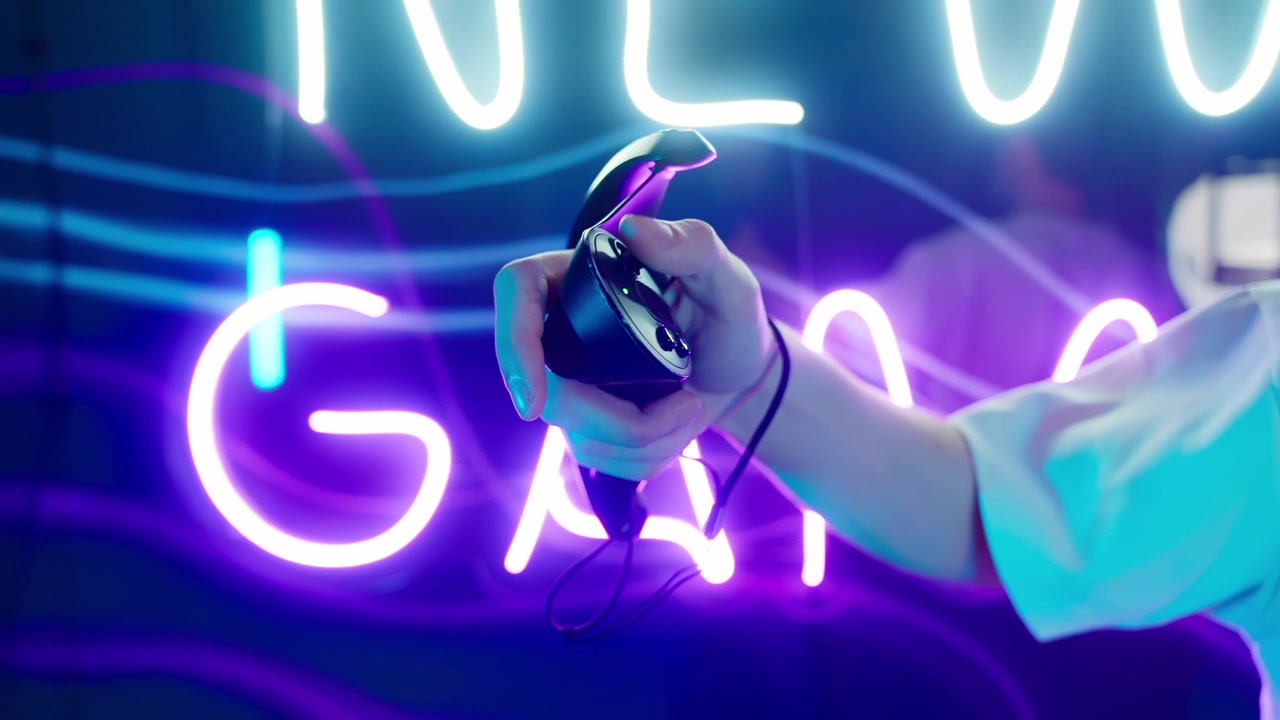 Primo piano di una mano che impugna un controller VR davanti a un'insegna al neon 'New Game'.