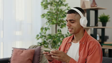 young man relaxing at home with headphones and smartphone