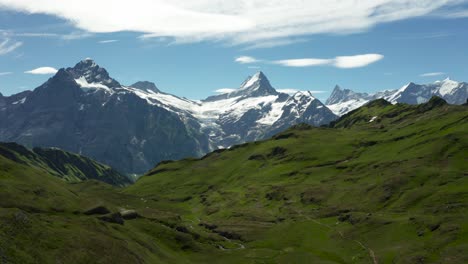 aerial view of beautiful mountain scenery with snow covered high mountain peaks and green grass during summer