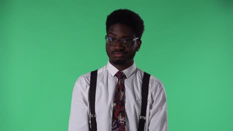 portrait of young african american man looking at camera, listening to boring information and yawning. black male with tie and glasses in white shirt posing on green screen in studio. close up