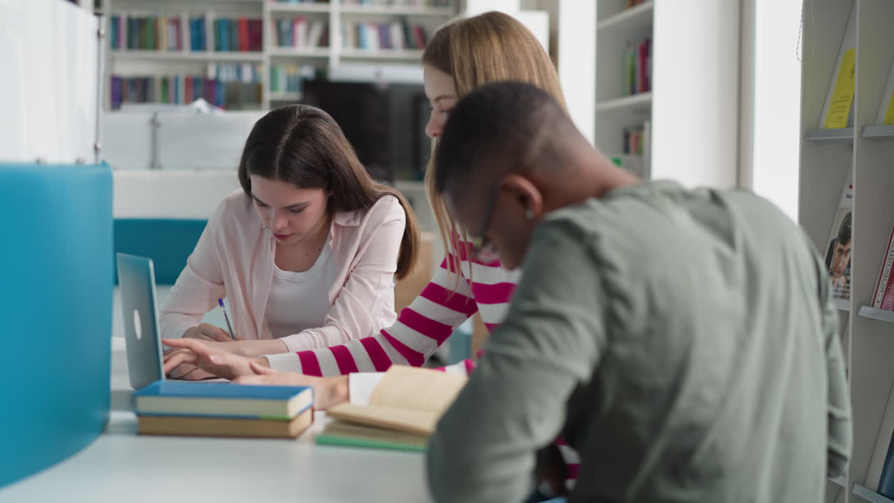 los estudiantes trabajan según la presentación en la biblioteca. los colegas escriben y navegan por internet mientras leen libros en la sala pública. diferentes fuentes y técnicas de educación para el trabajo de posgrado