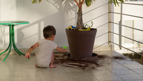 Junger-Frecher-Lateinischer-Junge,-Der-An-Einem-Sommernachmittag-Erde-Aus-Einem-Blumentopf-In-Diesem-Haus-Auf-Den-Boden-Fallen-Lässt