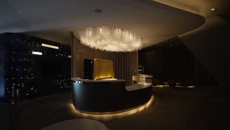 modern reception desk with a unique chandelier in a dimly lit, luxurious lobby