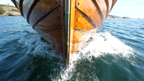 front of a wooden sjekte boat slicing through the waves - slow motion