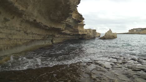 mediterranean sea waves rinse the limestone wall of il-kalanka beach in malta