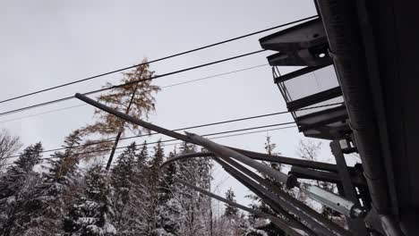 Panning-shot-across-snowy-Kasprowy-Wierch-cable-car-station-lines-and-snow-covered-woodland-wilderness