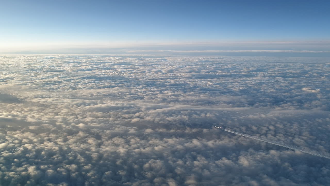 vista increíble desde la cabina de un avión que vuela alto por encima de las nubes dejando un largo rastro de aire de vapor de condensación blanco en el cielo azul