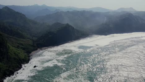 mountains and beaches on foggy coast of indonesia, aerial view