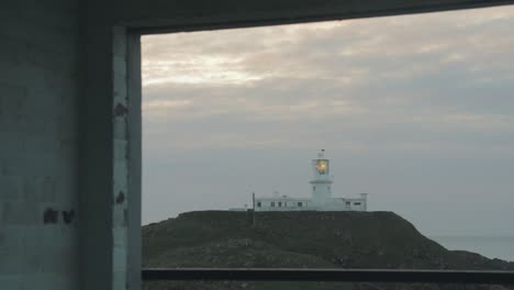 vista del faro a través de la ventana del edificio abandonado en la noche nublada