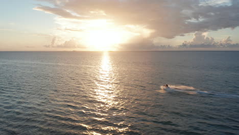 Aerial-fly-over-jet-ski-riders-full-speed-ride-on-caribbean-coast-together-have-fun-with-sunset-over-horizon